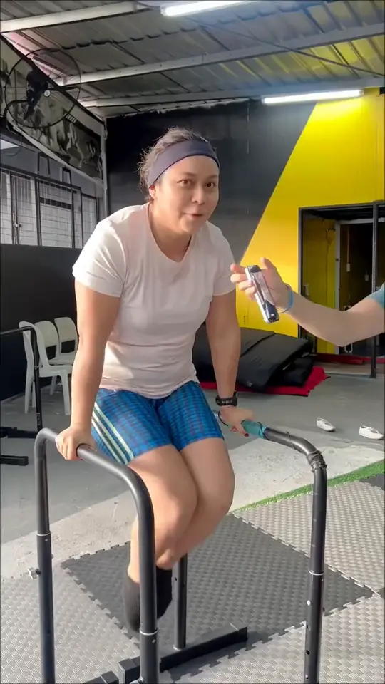 Alumna principiante haciendo fondos en paralelas con ayuda del coach
